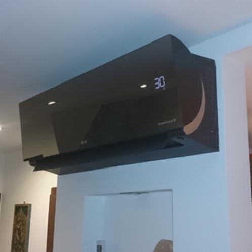 Czarna jednostka klimatyzacyjna LG Artcool Mirror z wyświetlaczem temperatury 30 stopni Celsjusza, zamontowana na białej ścianie wewnątrz pomieszczenia.