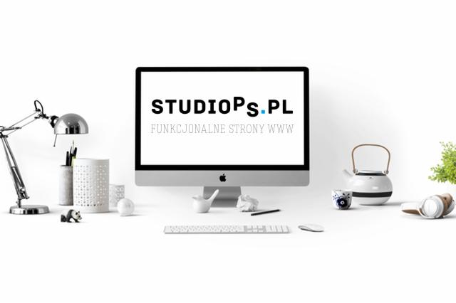 Minimalistyczne biurko z iMaciem wyświetlającym logo StudioPS.pl i hasło 'Funkcjonalne strony WWW', obok lampka, akcesoria biurowe, czajnik, słuchawki i roślina w doniczce.