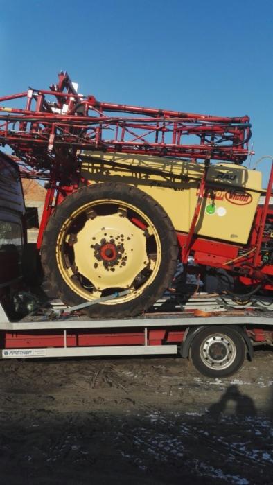 Żółto-czerwony opryskiwacz rolniczy marki RAU na czerwonej lawecie transportowej z widocznym logiem Partner.