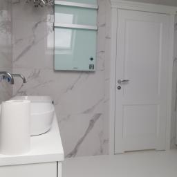 HYDROMASTERS - Nowoczesna łazienka z marmurowymi płytkami, szklanym grzejnikiem dekoracyjnym i białą armaturą, minimalistyczny design.