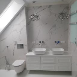 HYDROMASTERS - Nowoczesna łazienka na poddaszu z marmurowymi płytkami, podwójną umywalką nablatową na białej szafce, wiszącą toaletą i dekoracyjnymi lampami wiszącymi.