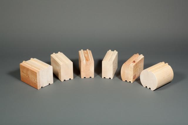 Różne profile bali drewnianych, w tym kwadratowe, prostokątne i okrągłe, pokazane na szarym tle, prezentujące system łączenia na pióro i wpust.