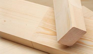 Dwa elementy z drewna konstrukcyjnego KVH: pozioma deska łączona na długości i pionowy kantówka z zaokrąglonymi krawędziami, widoczne słoje drewna.