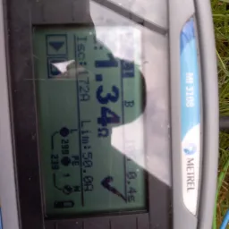 Wyświetlacz miernika elektrycznego Metrel MI 3108 z widocznymi wynikami pomiarów prądu zwarciowego (Isc: 1.72A) i impedancji pętli zwarcia (Lim: 50.0A) na tle trawy.