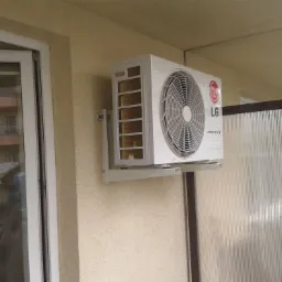 Klimatyzator LG Inverter V zamontowany na ścianie budynku w Szczytnie, widok z boku, z fragmentem okna i balkonu w tle.