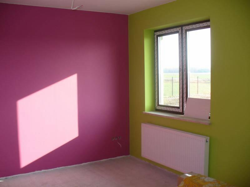 Pokój po malowaniu ścian na fuksjowy i limonkowy kolor, widoczny biały grzejnik pod oknem, cień w kształcie prostokąta na ścianie.