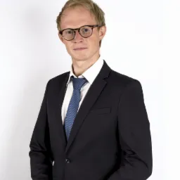 Portret mężczyzny w garniturze i okularach na białym tle, reprezentujący profesjonalizm w usługach prawnych w Zielonej Górze.