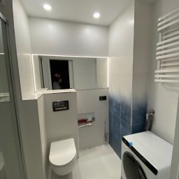 PIOFACH SPÓŁKA Z OGRANICZONĄ ODPOWIEDZIALNOŚCIĄ - Nowoczesna łazienka z białymi i niebieskimi płytkami ombre, podświetlanym lustrem, podwieszaną toaletą i pralką w folii ochronnej.