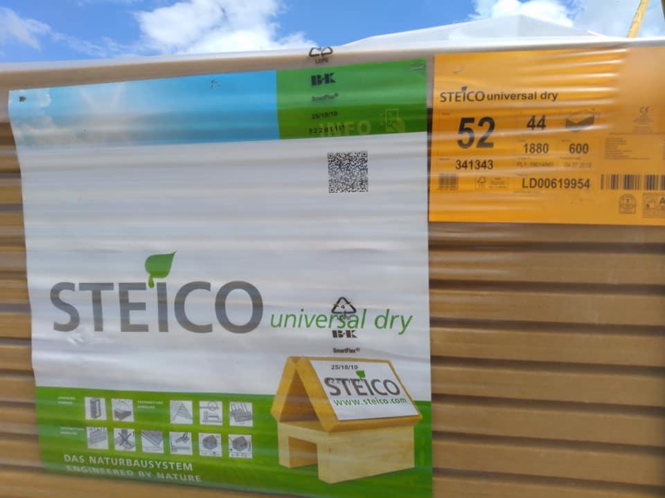 Paczka izolacji STEICO universal dry z widocznymi oznaczeniami producenta, kodem QR i informacjami o produkcie, na tle błękitnego nieba.