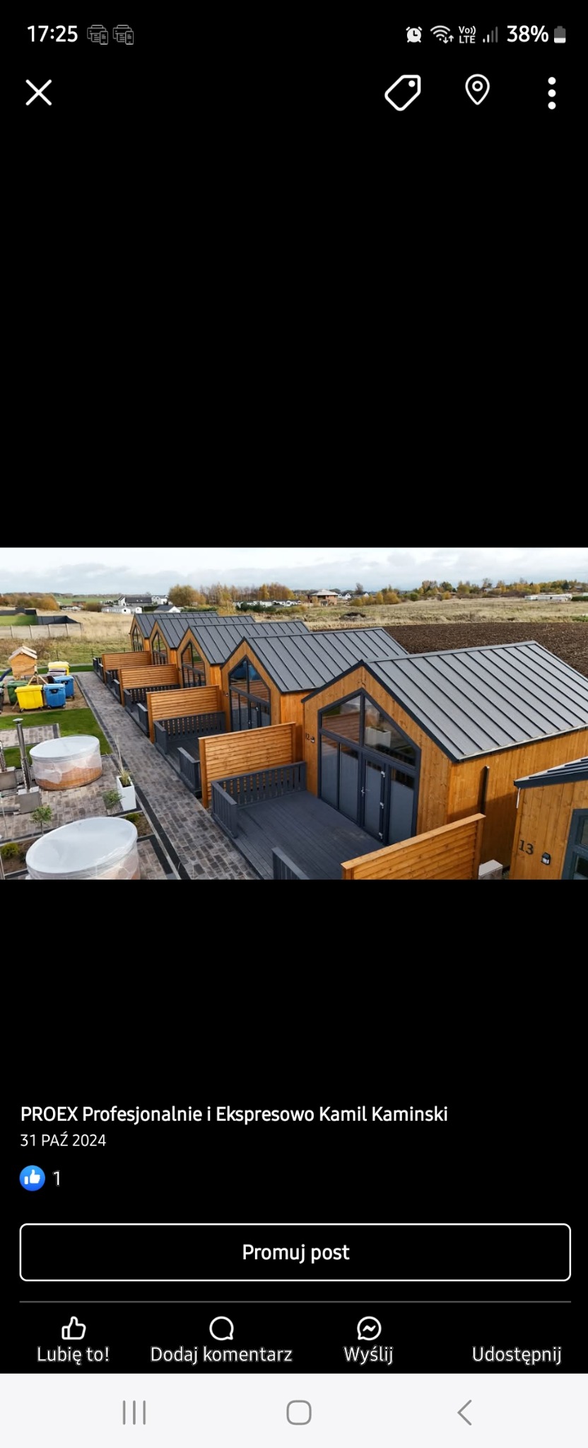 Kompleks kilku identycznych, drewnianych domków letniskowych z szarymi dachami i tarasami, otoczonych zielenią i z widocznymi jacuzzi na zewnątrz.