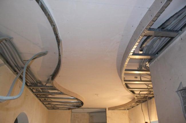 Nietypowa konstrukcja sufitu podwieszanego z płyt kartonowo-gipsowych z widocznymi profilami metalowymi i kablami, sufit w trakcie montażu.