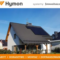 Dom jednorodzinny z zamontowanymi panelami fotowoltaicznymi na dachu, widoczne logo firmy Hymoń, błękitne niebo w tle.