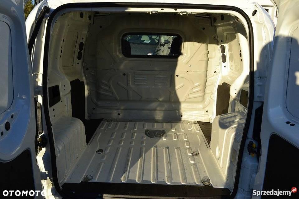 Wnętrze puste, białe przestrzeni ładunkowej dostawczego samochodu z otwartymi drzwiami, widoczne mocowania podłogowe i okno w przegrodzie.