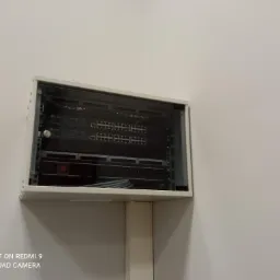 Szafa rack wisząca na ścianie, z widocznymi switchami sieciowymi TP-Link i okablowaniem, zamknięta na klucz.