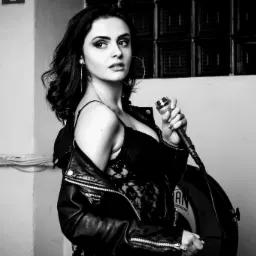 Czarno-białe zdjęcie kobiety z mikrofonem, ubrana w koronkową bluzkę i skórzaną kurtkę, z perkusją w tle