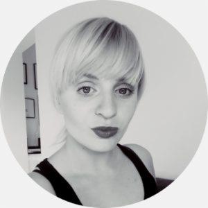 Portret kobiety z blond włosami, czerwonymi ustami i poważnym wyrazem twarzy, czarno-białe zdjęcie.