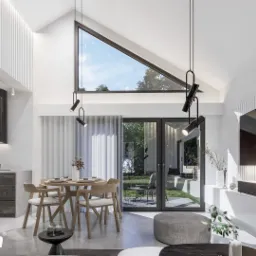 Jasne wnętrze domu z wysokim sufitem i trójkątnym oknem, minimalistyczna kuchnia z czarnym okapem, okrągły stół jadalny z drewnianymi krzesłami, duże przesuwne drzwi szklane z widokiem na ogród.