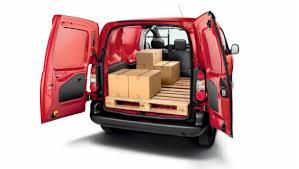 Wnętrze czerwonego furgonetki z otwartymi tylnymi drzwiami, załadowane paletą z kartonowymi pudłami.