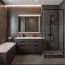 Usługi ogólnobudowlane - Nowoczesna łazienka w szarościach: płytki imitujące kamień, podświetlane lustro nad podwójną umywalką, kabina prysznicowa typu walk-in i wanna.