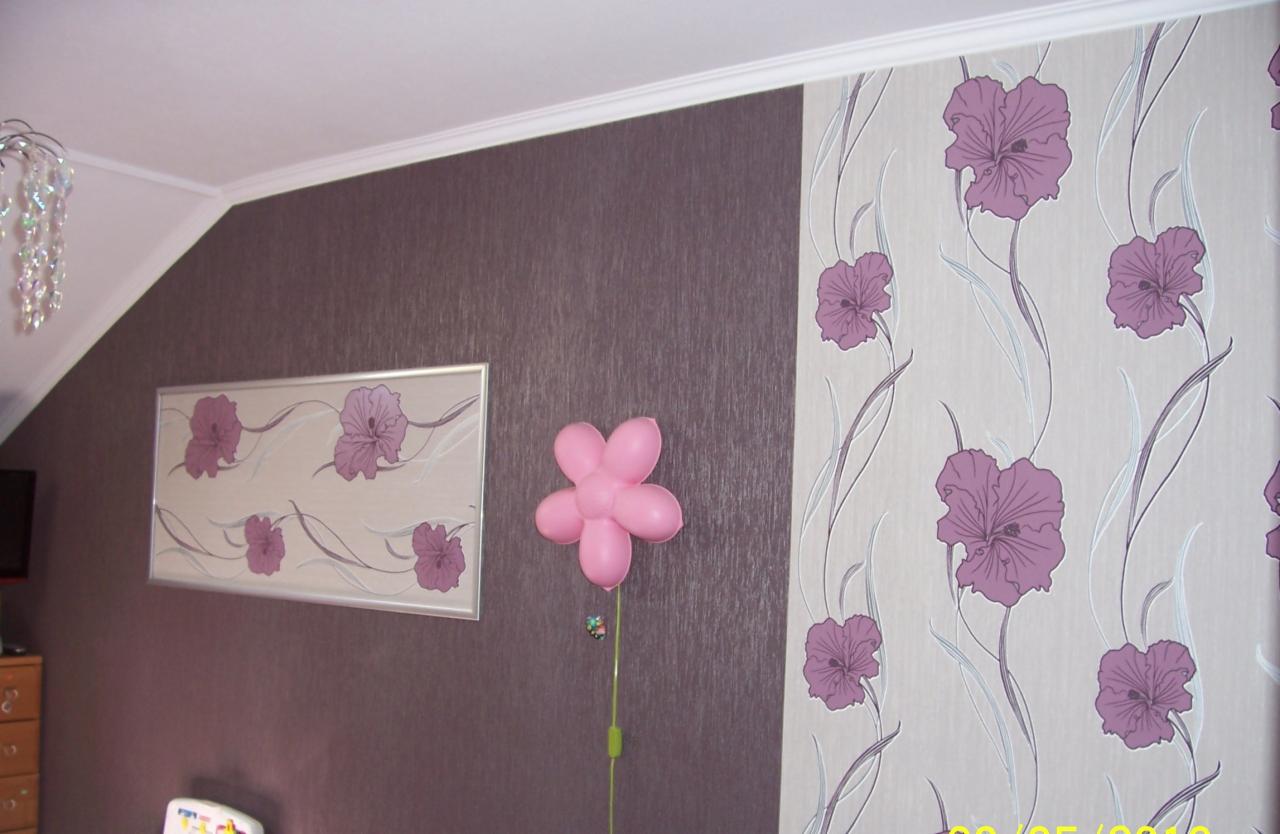Pokój po tapetowaniu: pionowy pas tapety w kwiaty i brązowa ściana, ozdobione obrazem i balonem w kształcie kwiatka.