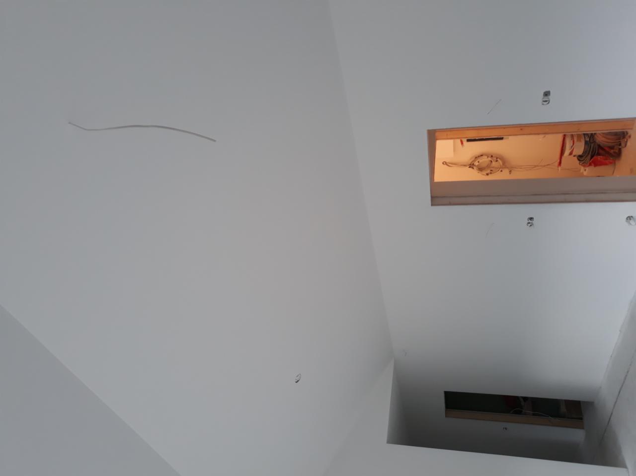 Biały sufit z dwoma otworami rewizyjnymi, widoczne przewody elektryczne wewnątrz, świeżo pomalowana powierzchnia.