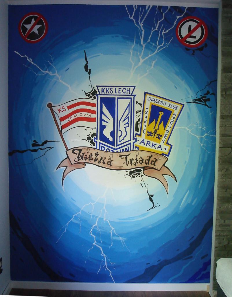 Malowidło na ścianie z symbolami klubów sportowych: KS Cracovia, KKS Lech Poznań i Arka Gdynia, umieszczone na tle z efektem błyskawic i napis 'Wielka Triada'.