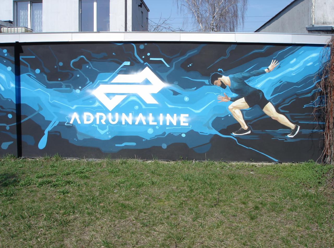Graffiti na ścianie przedstawiające logo 'ADRUNALINE' i postać biegacza w dynamicznej pozie, utrzymane w odcieniach błękitu i czerni.