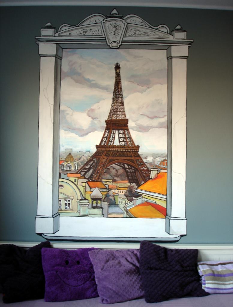 Iluzjonistyczne przedstawienie wieży Eiffla na ścianie, imitujące okno z widokiem na Paryż, z dekoracyjną ramą i poduszkami w odcieniach fioletu u dołu.