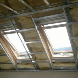 Szkielet metalowy pod płyty gipsowe, wypełniony materiałem izolacyjnym, widoczne dwa okna dachowe w skośnej części poddasza.