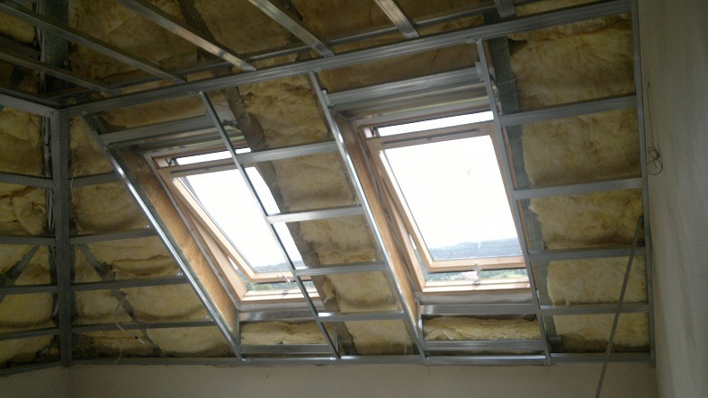 Szkielet metalowy pod płyty gipsowe, wypełniony materiałem izolacyjnym, widoczne dwa okna dachowe w skośnej części poddasza.