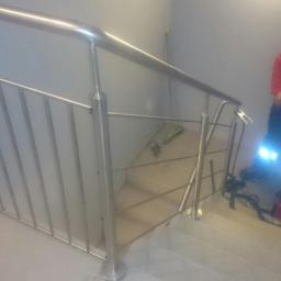 Dark Metal - Montaż balustrady nierdzewnej na schodach przez spawacza w masce ochronnej, widoczny sprzęt spawalniczy i elementy konstrukcyjne.