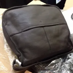 Brązowa, skórzana torba męska w Gdańsku, sfotografowana z góry na brudnym kartonie i folii bąbelkowej, widoczne szwy i zamek błyskawiczny.