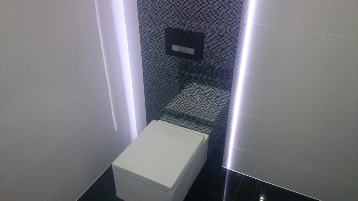 Nowoczesna toaleta podwieszana z mozaiką i podświetleniem LED w wykończonej łazience, widok z góry.