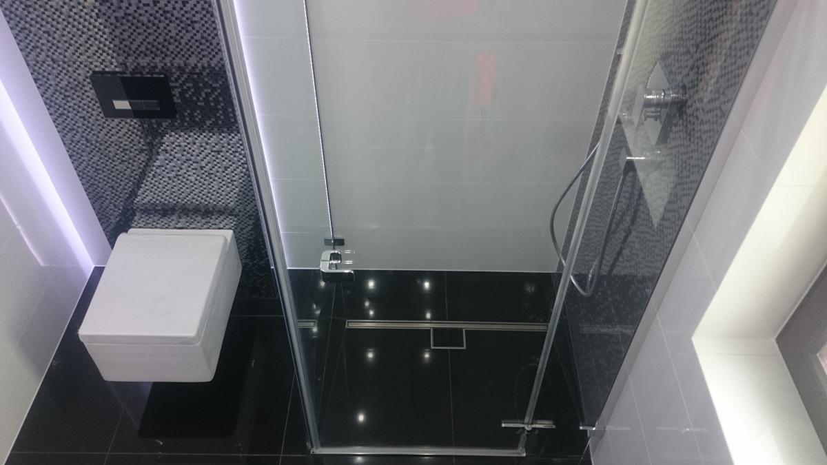 Nowoczesna łazienka z kabiną prysznicową typu walk-in, wiszącą miską WC i mozaiką na ścianie, czarno-biała kolorystyka, podświetlenie LED.