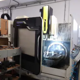 Centrum obróbcze CNC DMU 50 ecoline w trakcie pracy, widoczny obrabiany element zamocowany na stole, panel sterowania maszyny po prawej stronie, warsztatowe otoczenie.