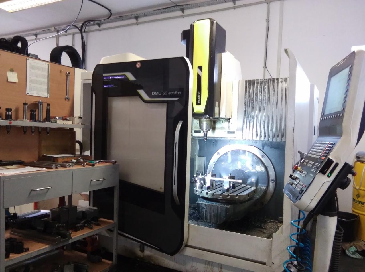 Centrum obróbcze CNC DMU 50 ecoline w trakcie pracy, widoczny obrabiany element zamocowany na stole, panel sterowania maszyny po prawej stronie, warsztatowe otoczenie.