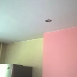 Pomieszczenie po malowaniu z oświetleniem punktowym na suficie i ścianą pomalowaną na r&oacute;żowo.