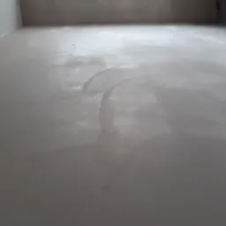 Świeżo wylana, mokra posadzka cementowa w szarym pomieszczeniu, widoczne ślady po rozprowadzaniu masy.