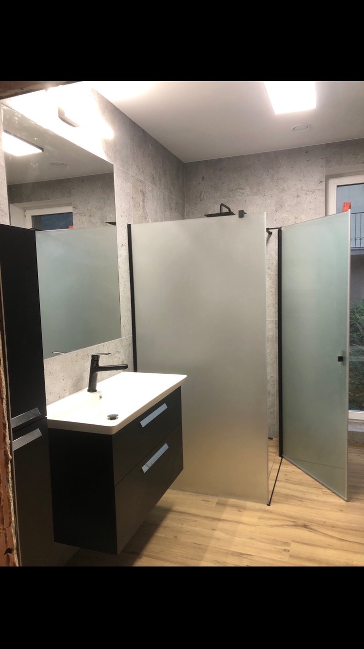 Nowoczesna łazienka z szarą armaturą, umywalką nablatową i kabiną prysznicową z matowego szkła, wykończona w odcieniach szarości i beżu.