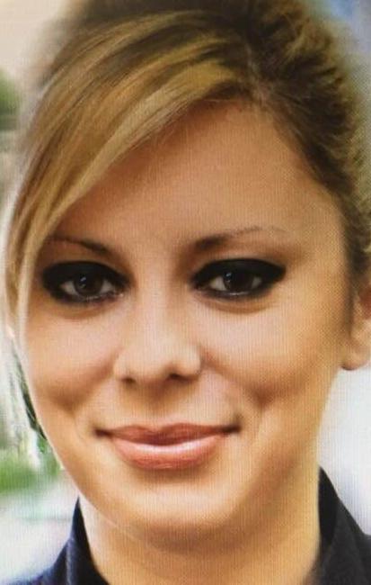 Portret kobiety z blond włosami, ciemnym makijażem oczu i delikatnym uśmiechem, skierowanej wprost.