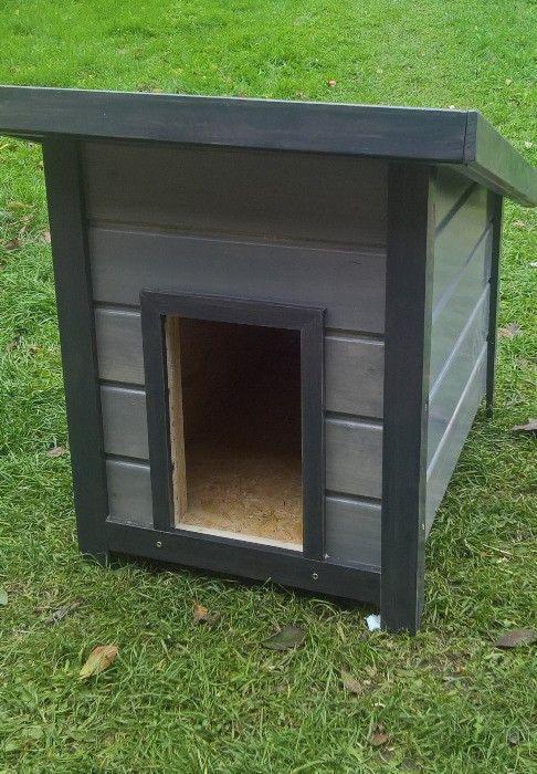 Drewniana buda dla psa z ciemnoszarą impregnacją, ustawiona na trawniku.