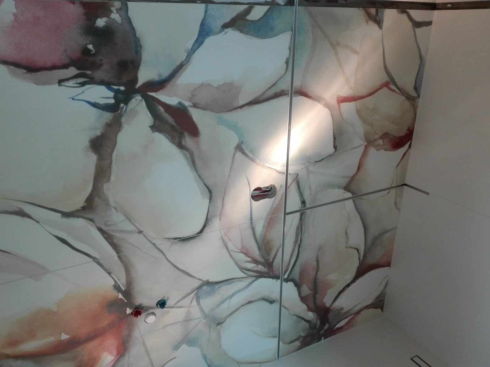 Biały sufit z motywem akwarelowych kwiatów, widoczne otwory na oświetlenie i fragment szklanej kabiny prysznicowej. Nietypowe wykończenie wnętrza łazienki.