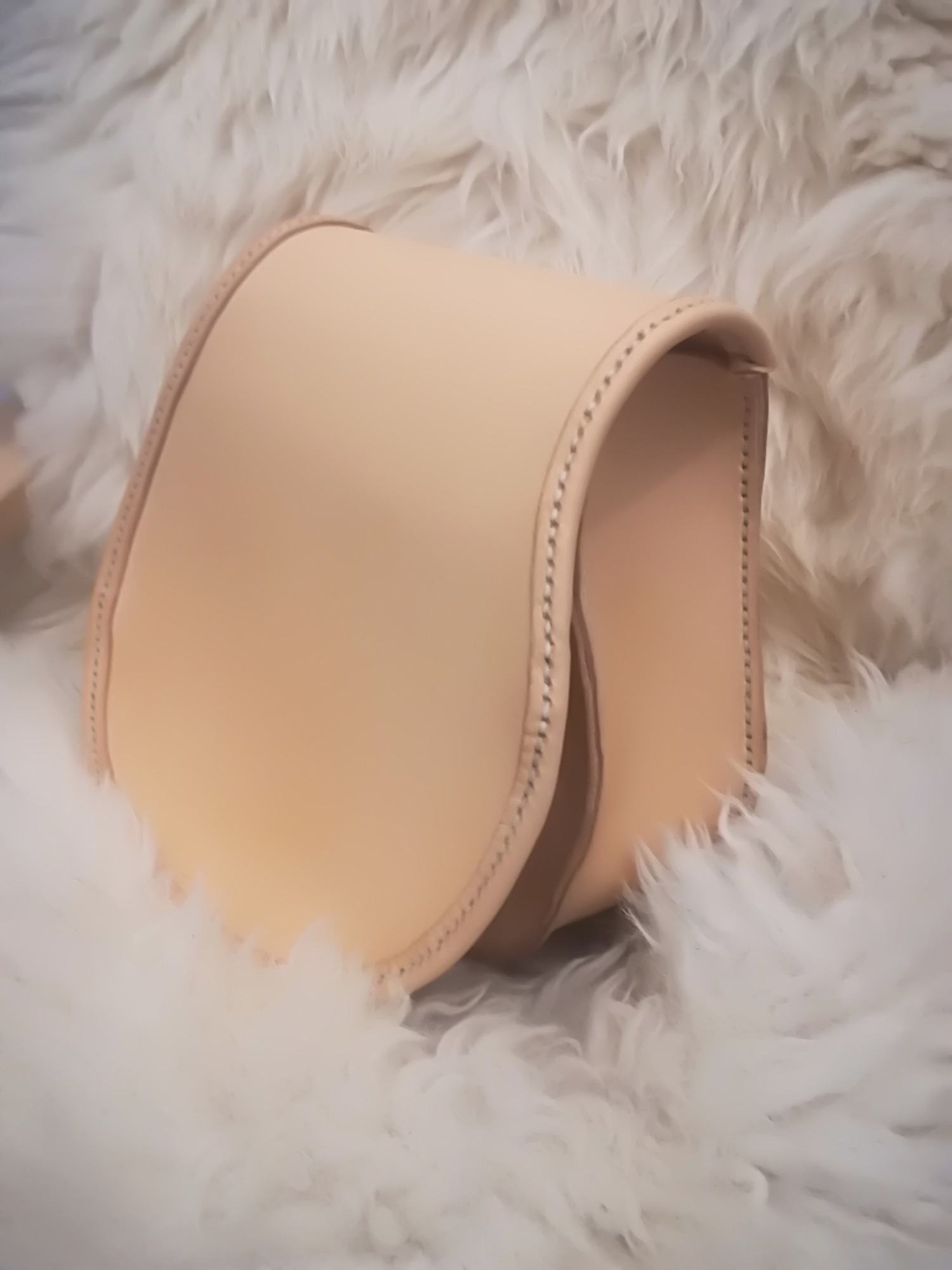 Jasna, skórzana torebka damska z ozdobnym przeszyciem, wykonana przez kaletnika z Kamienia Pomorskiego, prezentowana na puszystym, białym tle.