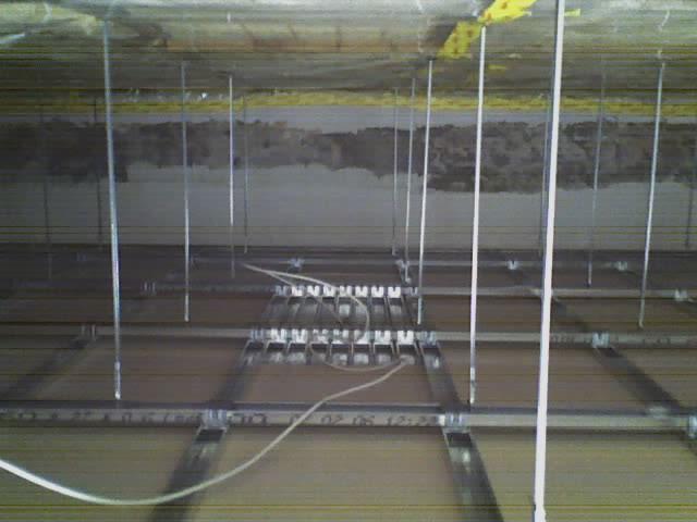 Montaż stelażu sufitu podwieszanego z płyt karton gips, widoczne profile metalowe, zawiesia i przewody elektryczne.