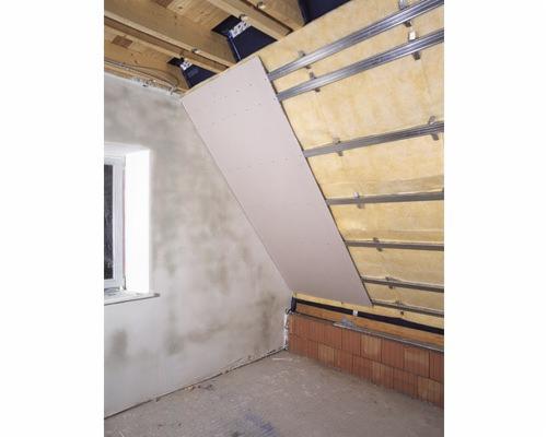 Montaż płyty gipsowo-kartonowej na poddaszu, widoczne ocieplenie wełną mineralną i metalowy stelaż, surowa ściana z oknem w tle.