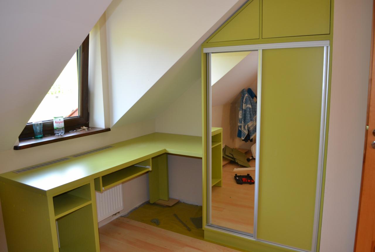 Zielony narożny biurko i szafa przesuwna w pokoju na poddaszu, widoczne narzędzia i niedokończone wykończenie podłogi.