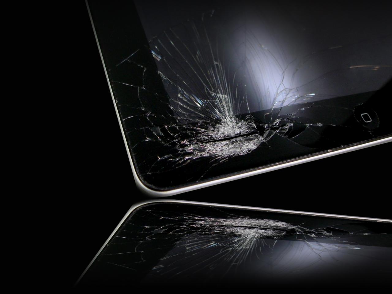 Rozbity ekran tabletu z widocznym pęknięciem w prawym górnym rogu i odbiciem na błyszczącym czarnym tle.