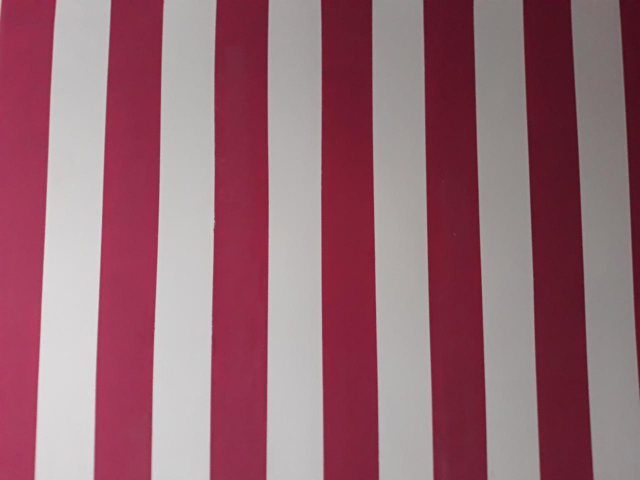 Równomierny układ pionowych pasów w kolorze białym i różowym, tworzący wzór na ścianie.