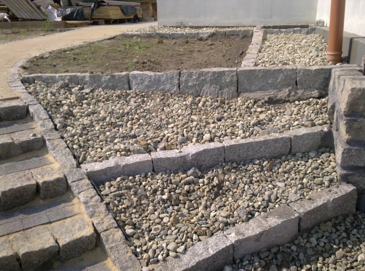 Kamienne schody i rabaty z grysem, wykonane w Katowicach, z widoczną kostką granitową i ziemią przygotowaną pod nasadzenia.