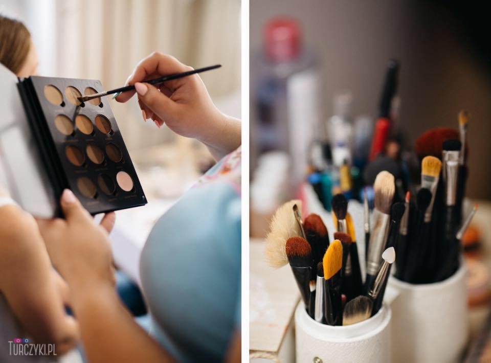 Osoba aplikuje pędzlem cień z palety brązów; w tle pojemniki z pędzlami do wizażu.